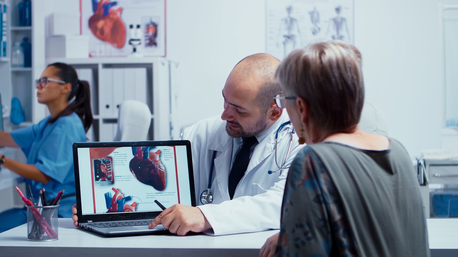 Cardiologist reviewing heart imaging on laptop with patient - cardiology practice IT services