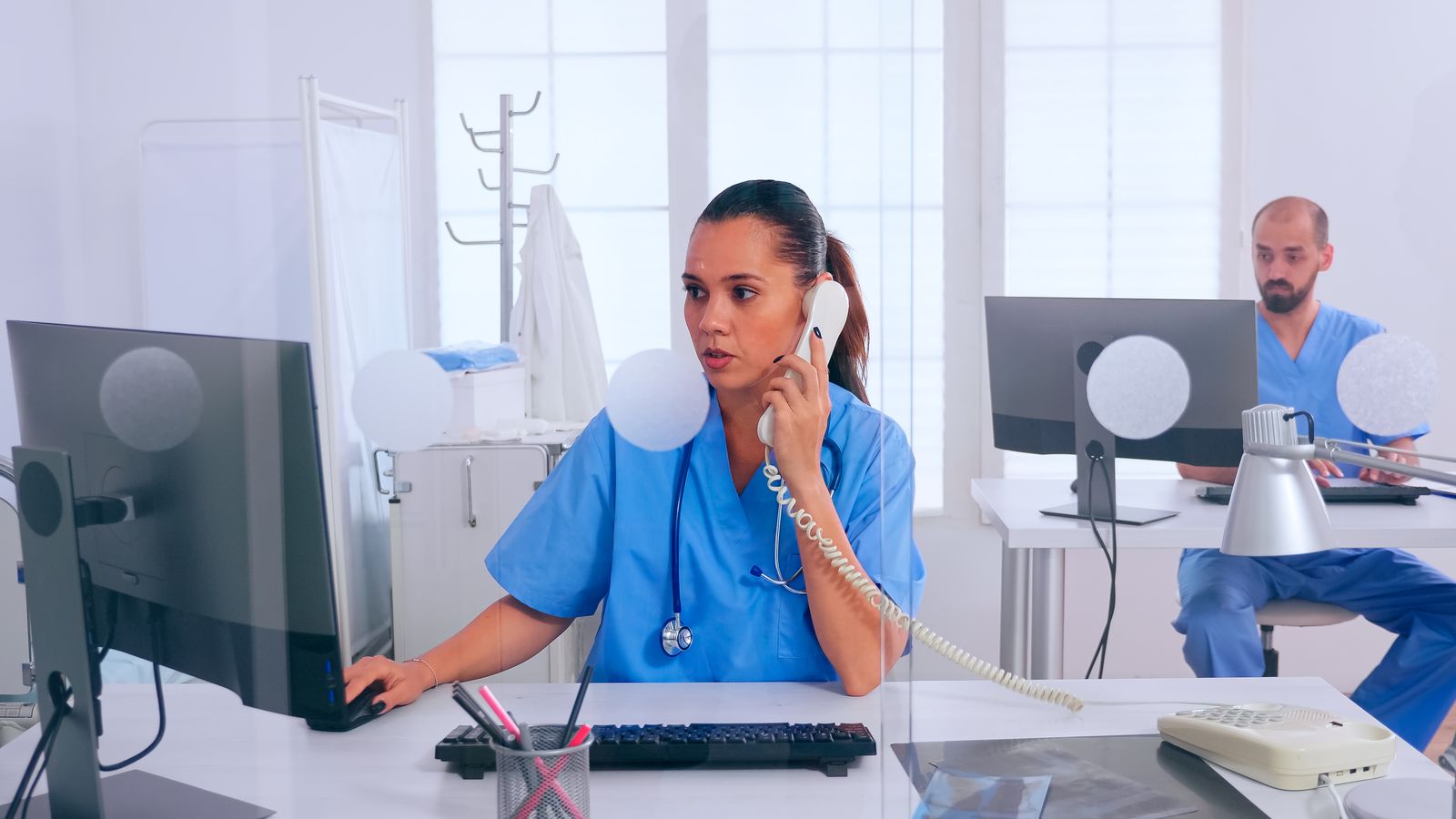 Front desk staff scheduling patients at computer - medical office technology