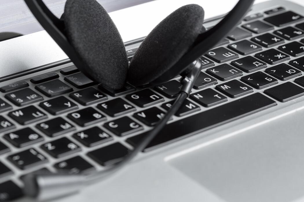 Headset resting on a laptop keyboard in a medical transcription home office
