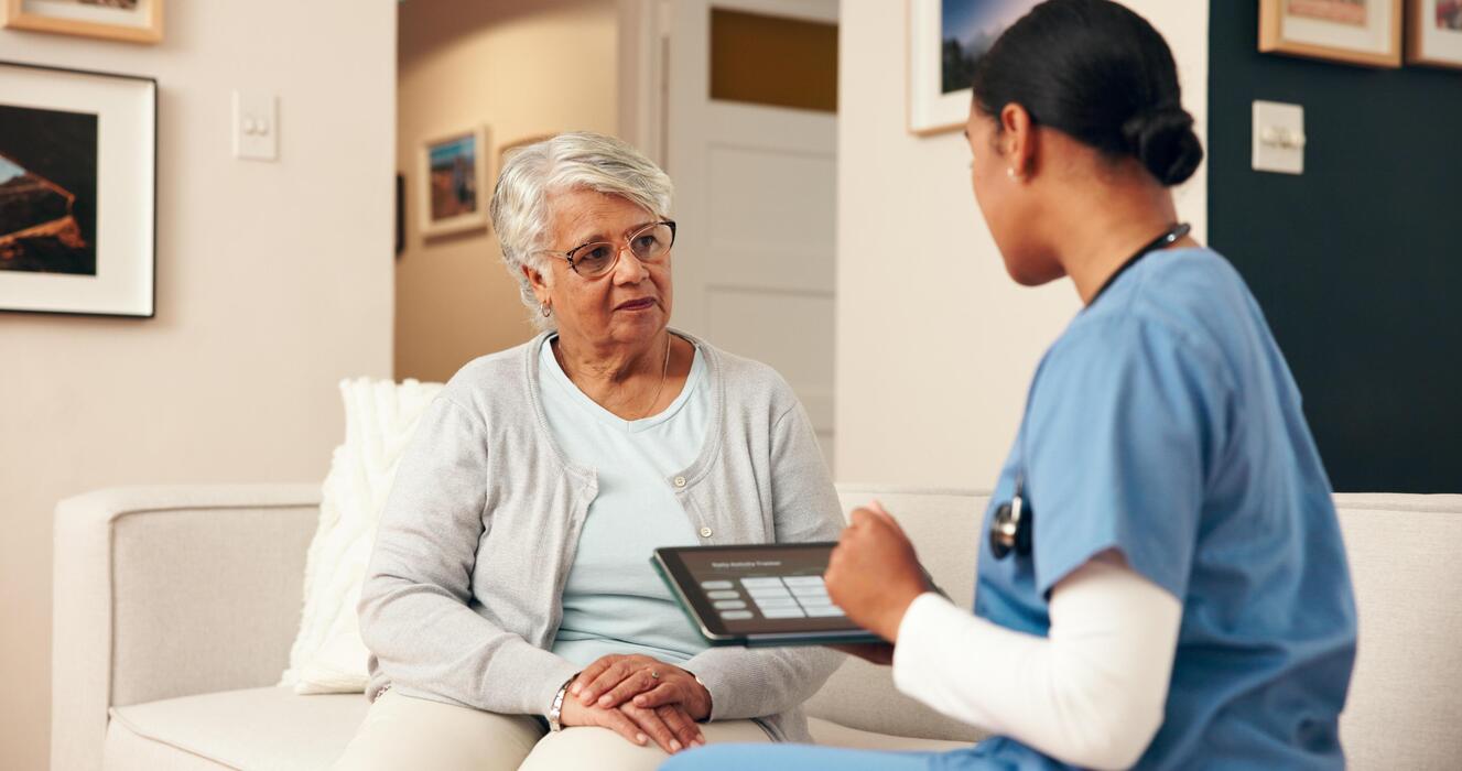 Mobile primary care IT support Home-visit nurse with a tablet caring for a senior patient at home