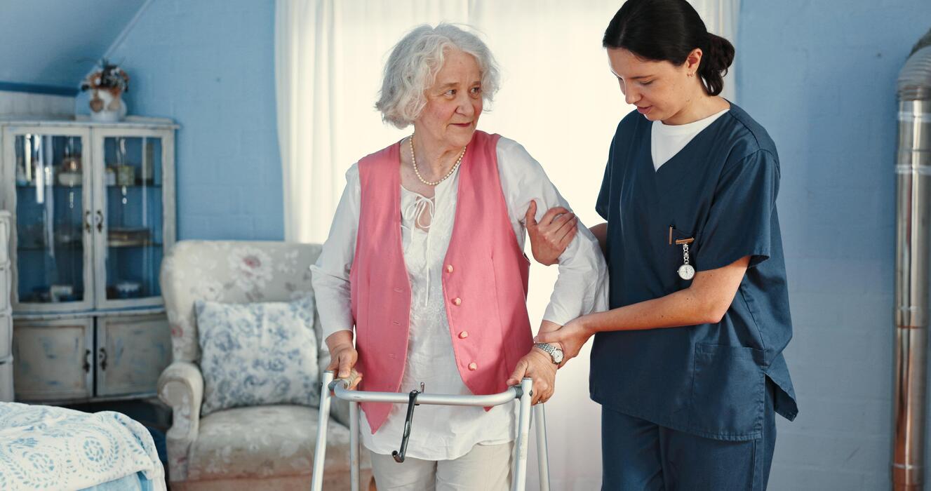 Caregiver helping an elderly woman with her walker during a home care visit