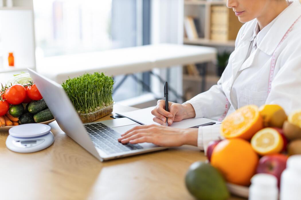 Nutrition and dietitian practice IT support Dietitian working on a laptop surrounded by fresh food at a nutrition practice