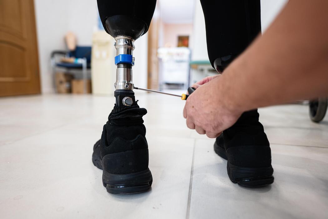 Technician adjusting a prosthetic leg for a proper fit at an O and P clinic