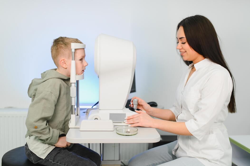 Optometrist performing an eye exam on a young boy at a pediatric ophthalmology clinic