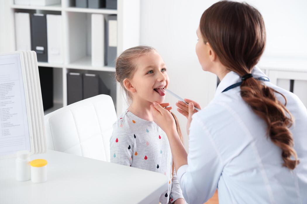 Doctor examining a sick childs throat during a walk-in visit at a pediatric urgent care center