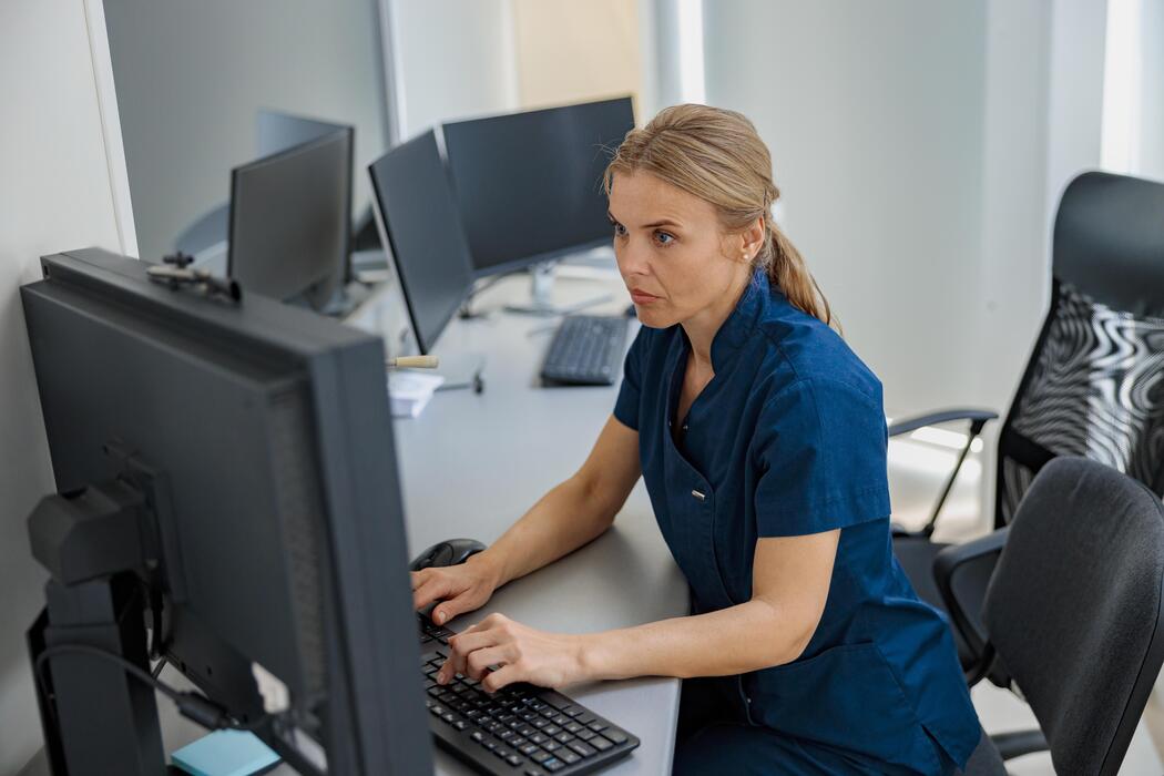 Physiatry practices IT support Clinical staff member working on a computer at the reception desk of a modern physiatry practice