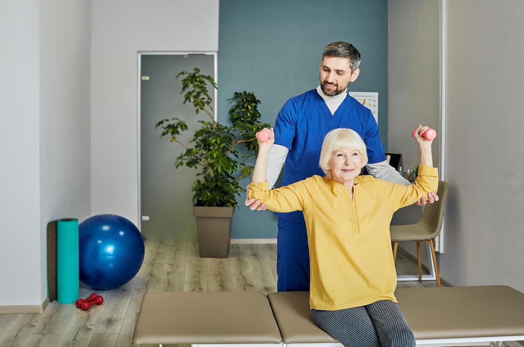 Physiotherapist guiding a senior patient through strengthening exercises at a physical medicine and rehabilitation practice