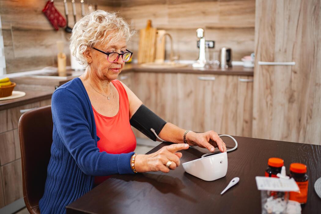 Senior patient taking a blood pressure reading at home with a connected remote patient monitoring device
