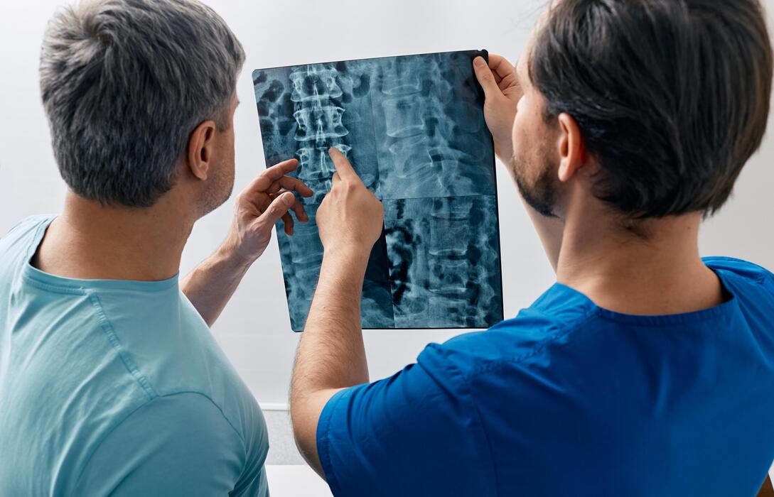 Spine Specialist Reviewing X-Ray Spine specialist reviewing a backbone X-ray with a patient