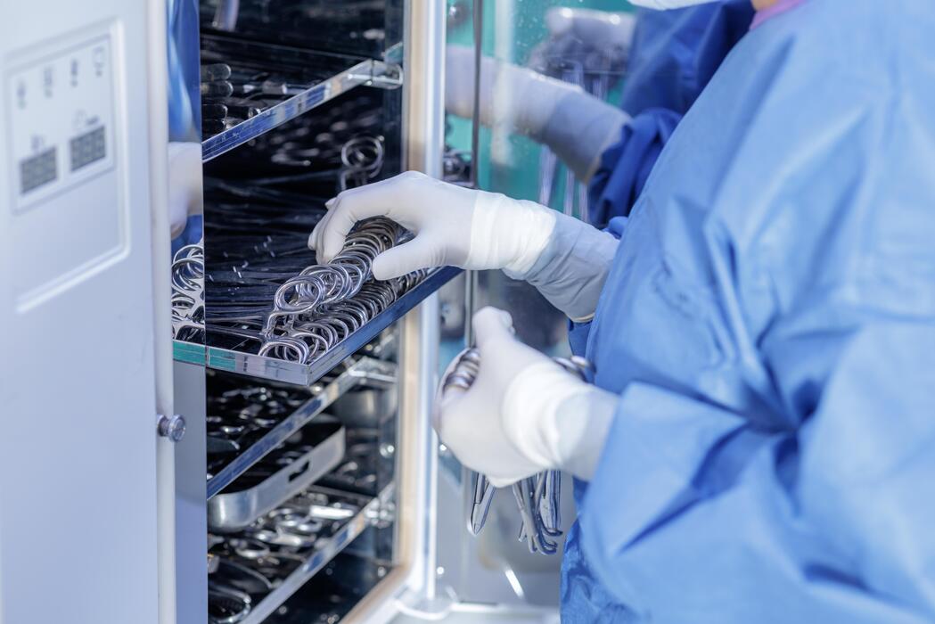 Sterile Processing Autoclave Loading Technician loading surgical instruments into a sterilizer in a sterile processing department